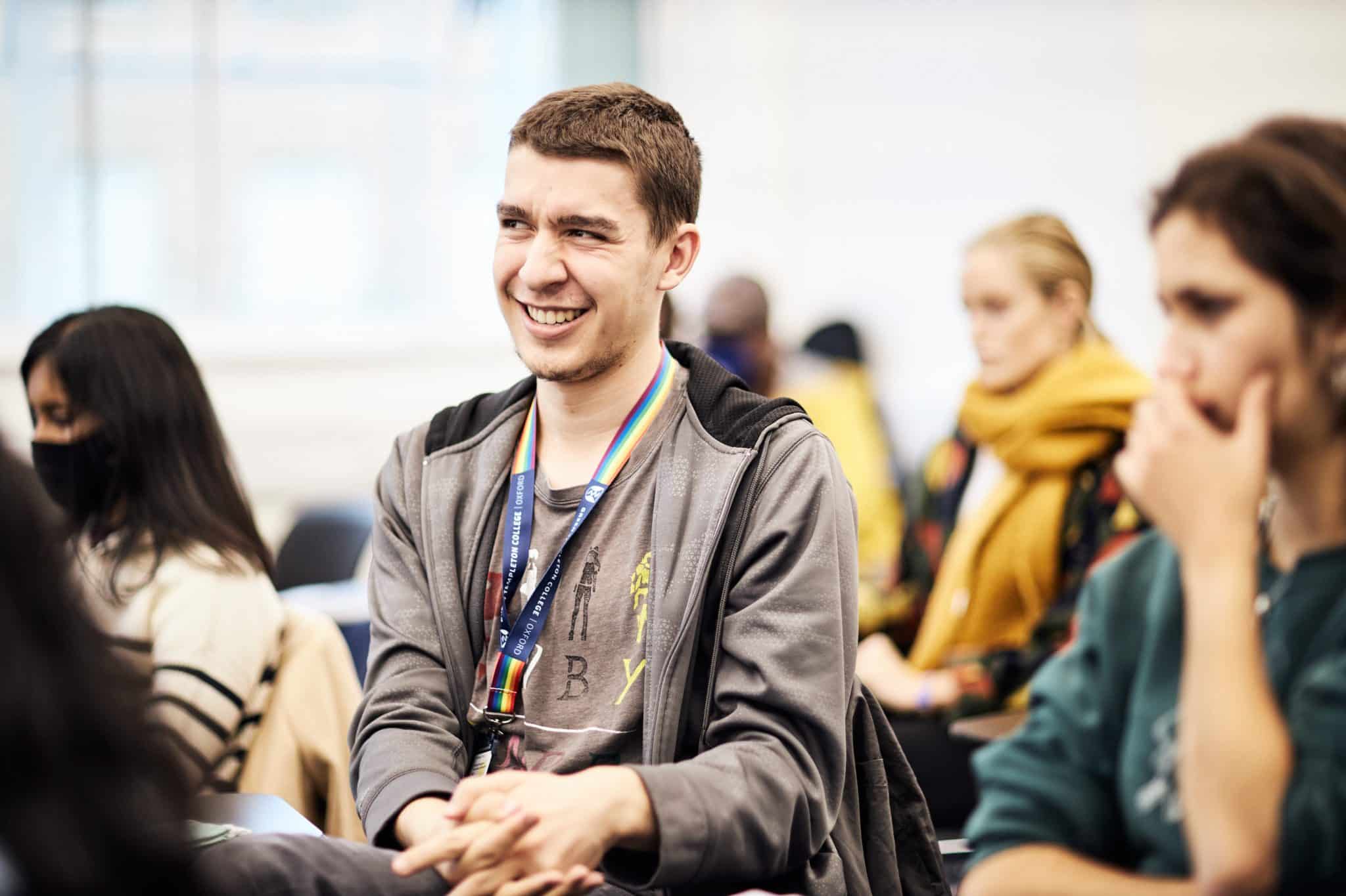 A smiling man amongst other students at a lecture